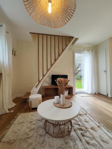 a living room with a table and a staircase at Le Bel Abri in Boulleville