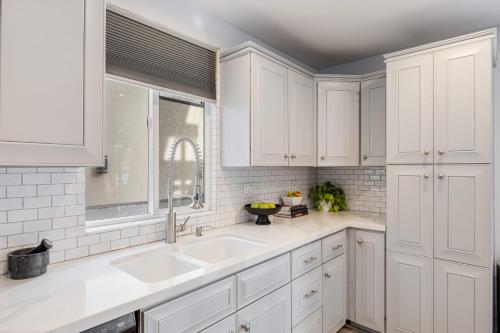 a kitchen with white cabinets and a sink at Sandy by AvantStay Oceanview Steps to Beach Patio w Fire Pit Dining Area in Newport Beach