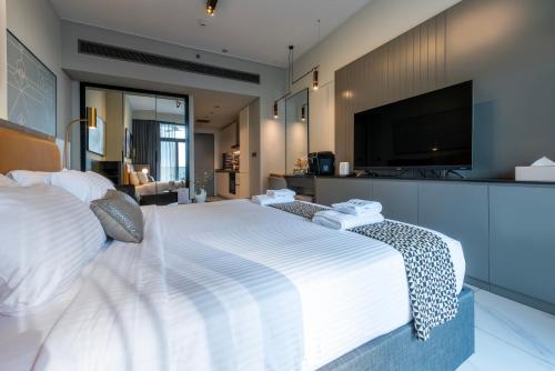 a bedroom with a large white bed with a flat screen tv at Canal View Studio Downtown - Near Dubai Mall & Burj Khalifa - MAG 318 in Dubai