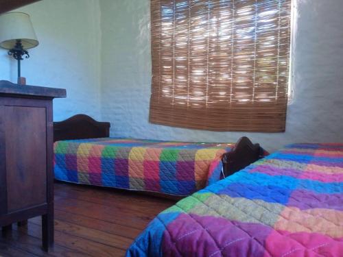 a bedroom with two beds and a window with a colorful blanket at casa y monoambiente Britopolis in Fomento