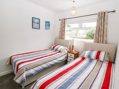two beds in a room with a window at H Jem in Benllech
