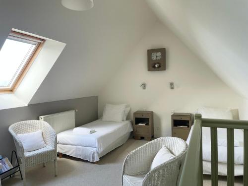 a bedroom with a bed and two chairs and a clock at Fleur & Mer in Montfarville