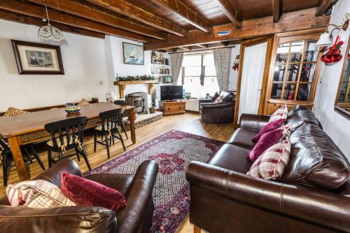 a living room with a leather couch and a table at Captain Cook's Cottage, Staithes, North Yorkshire in Staithes