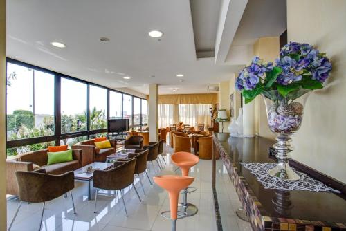 - un hall avec des tables, des chaises et un vase de fleurs dans l'établissement Hotel Deanna, à Bellaria-Igea Marina