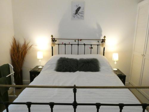 a bedroom with a bed with white sheets and two lamps at Fern Villa in Conwy