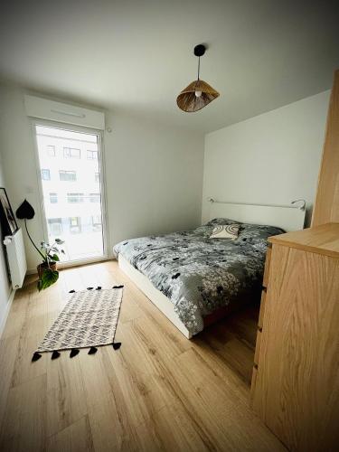 une chambre avec un lit et une grande fenêtre dans l'établissement Appartement Vannes Odyssée, à Vannes