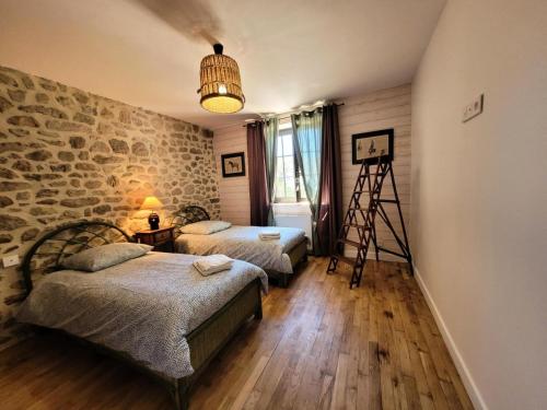 a room with two beds and a stone wall at Gîte de France Gîte bournabas 4 épis - Gîte de France 8 personnes MAE-6491 in Les Bournas