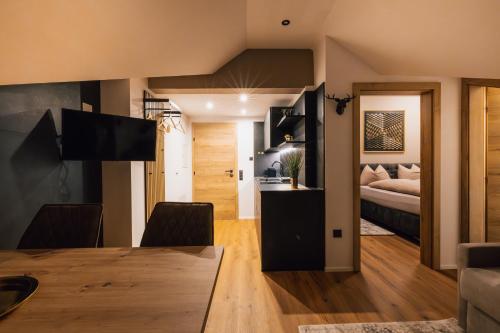 a living room with a dining room table and a bedroom at Posthof - Alpine Living Apartments in Campo di Trens