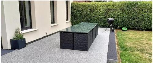 a glass table on a patio next to a building at Gite de la Fauvelière in Touffreville-la-Corbeline