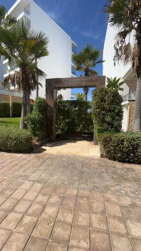 a stone walkway in front of a building with palm trees at Seaside studio with pool in Dar Bouazza