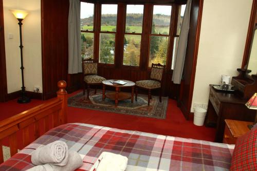 a bedroom with a bed and two chairs and a table at The Retreat Hotel in Strathpeffer