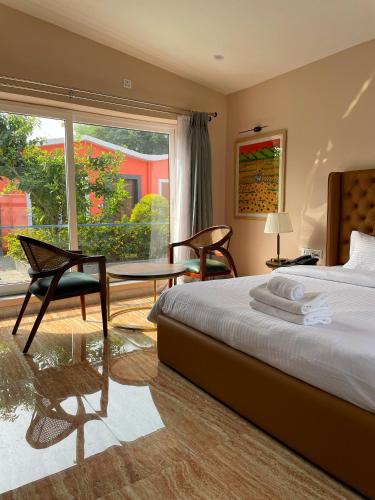 瓦拉纳西The VIA VARANASI Resort的一间卧室，配有一张床、一张桌子和几把椅子
