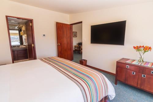 a bedroom with a bed and a tv on a wall at GHL Hotel Lago Titicaca in Puno