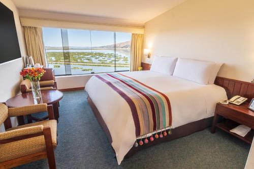 a hotel room with a large bed and a large window at GHL Hotel Lago Titicaca in Puno