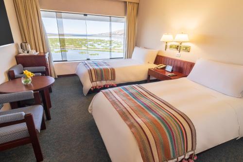 a hotel room with two beds and a window at GHL Hotel Lago Titicaca in Puno