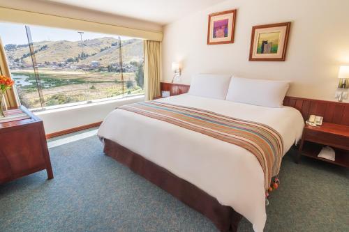 a large bed in a hotel room with a large window at GHL Hotel Lago Titicaca in Puno