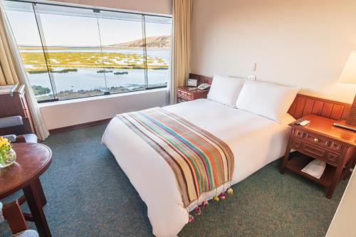 a hotel room with a large bed and a large window at GHL Hotel Lago Titicaca in Puno