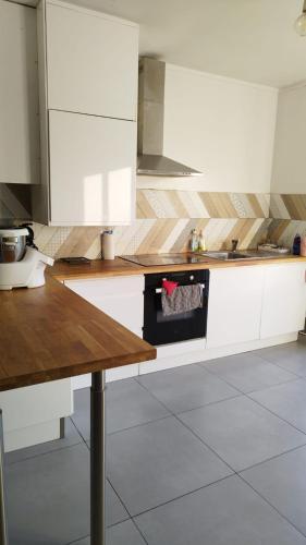 une cuisine avec des armoires blanches et un comptoir en bois dans l'établissement Cozy House, à Angers