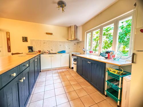 Il comprend une cuisine avec des placards bleus et du carrelage. dans l'établissement Maison en forêt, calme, proche village et piste cyclable - meublé 3 étoiles, à Uza