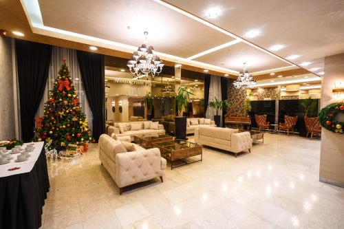a christmas tree in a living room with a christmas tree at Hotel Monogram Park in Ruma