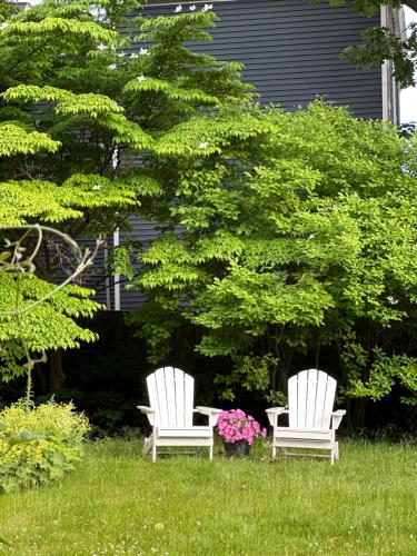 two white chairs sitting in the grass near a tree at The Underwood-Hale House in Providence