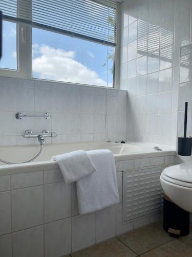 a white bathroom with a tub and a sink at Wiltsangh Bungalow in De Waal