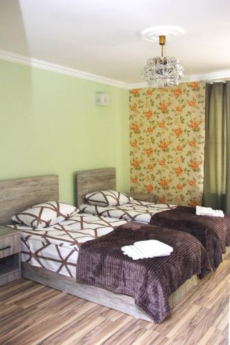 two beds in a room with green walls and a chandelier at Old Friends Cozy House in Gyumri