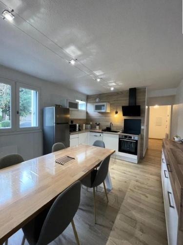 une grande cuisine avec une table et des chaises en bois dans l'établissement Résidence Le Palos - A deux pas du centre appartement 6 personnes à la Résidence PALOS A/62 MAE-6811, à Cadeilhan-Trachère