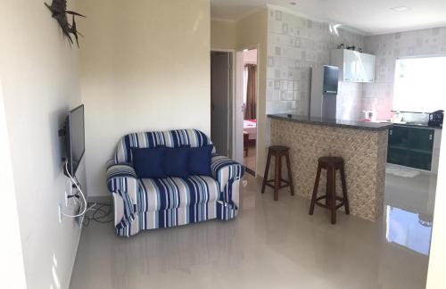 a living room with a chair and a kitchen at Seu Segundo Lar in Valença