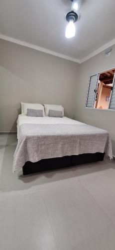 a white bedroom with a large bed with two pillows at Xodó do Litoral in Caraguatatuba