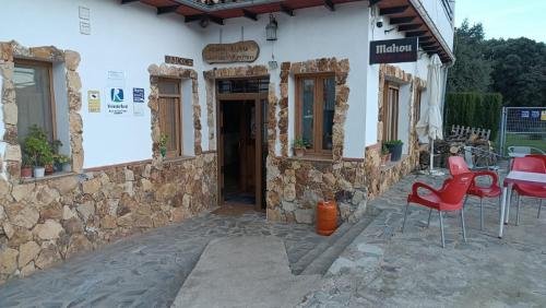a building with red chairs and a table outside at Dulce Posada in Cazorla