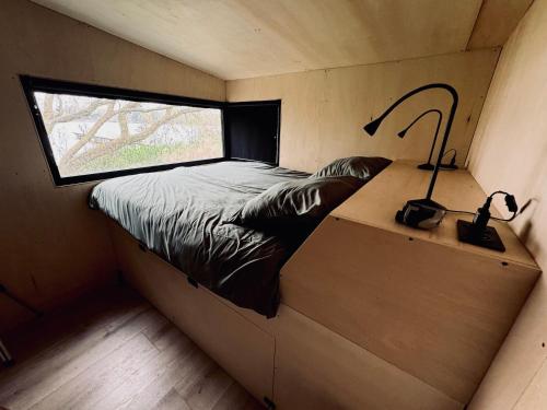 un lit dans une petite pièce avec une fenêtre dans l'établissement Le refuge du lac, à Féchain
