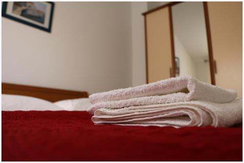 einen Haufen weißer Handtücher auf einem Bett in der Unterkunft Apartments Rupe in Primošten