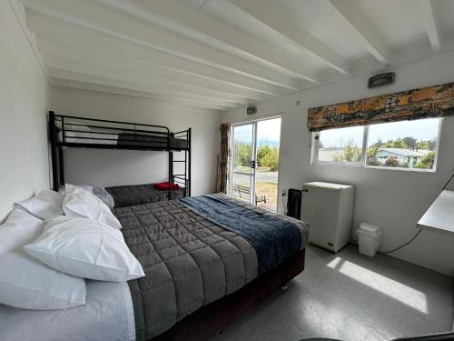 a bedroom with a bed and a large window at Waikuku Beach Holiday Park in Waikuku Beach