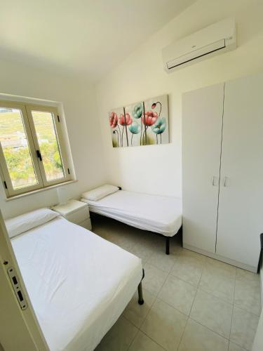 a white bedroom with two beds and a window at Marasusa Apartments Scirocco 226CW in Parghelia