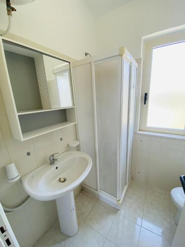 a white bathroom with a sink and a shower at Marasusa Apartments Scirocco 226CW in Parghelia