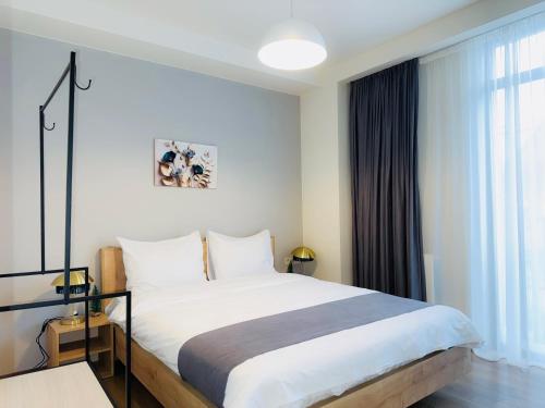 a bedroom with a large white bed and a window at HOTEL ARCHI KOKHTA BAKURIANI in Bakuriani
