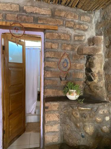 a bathroom with a door and a stone wall at Casapueblo in Cachí