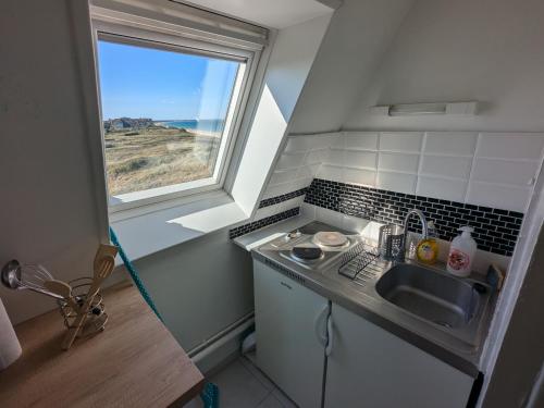 une petite cuisine avec un évier et une fenêtre dans l'établissement Appartement vue sur mer et accès direct à la plage, à Cabourg