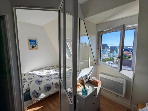 une petite chambre avec un lit et un miroir dans l'établissement Appartement vue sur mer et accès direct à la plage, à Cabourg