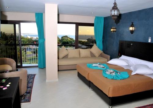 een slaapkamer met een groot bed en een bank bij Suite Hotel Tilila in Agadir