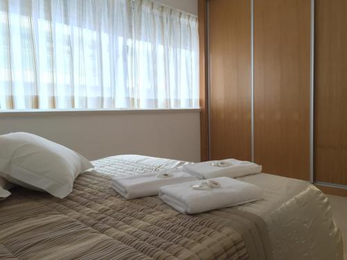1 cama con 2 toallas y ventana en Galante Beach Apartment, en Figueira da Foz