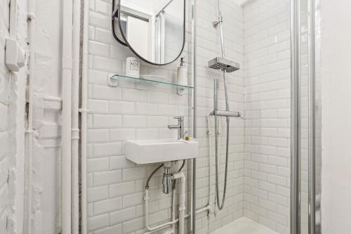une salle de bain blanche avec un lavabo et une douche dans l'établissement Charmant studio Beaugrenelle, à Paris