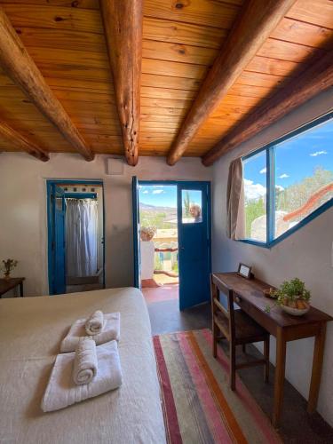 a bedroom with a bed and a desk and windows at Casapueblo in Cachí