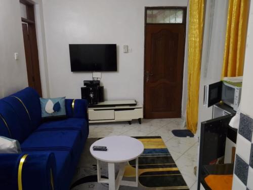 a living room with a blue couch and a tv at La-mia-casa in Mombasa