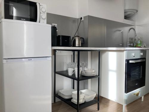 La cuisine est équipée d'un comptoir avec de la vaisselle et d'un réfrigérateur. dans l'établissement A4 Premier étage spacieux et lumineux, à Évaux-les-Bains