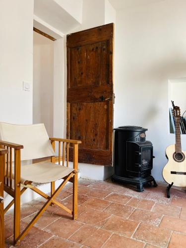 a room with a stove and a chair and a guitar at Remparts House in Mailhac