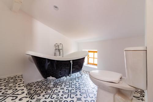 a bathroom with a black tub and a toilet at Remparts House in Mailhac