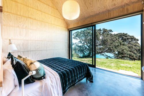 a bedroom with a bed and a large window at Mawhiti - Stay Waiheke in Waiheke Island