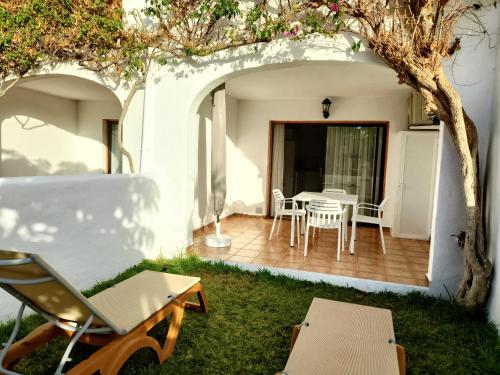 Un patio con una mesa y sillas y un árbol. en FAIRWAYS CLUB, suite B37, en San Miguel de Abona